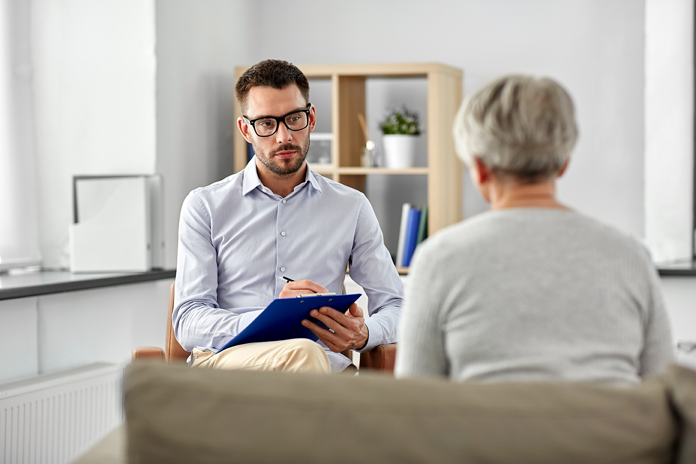 Psychologist with notebook listening intently to client